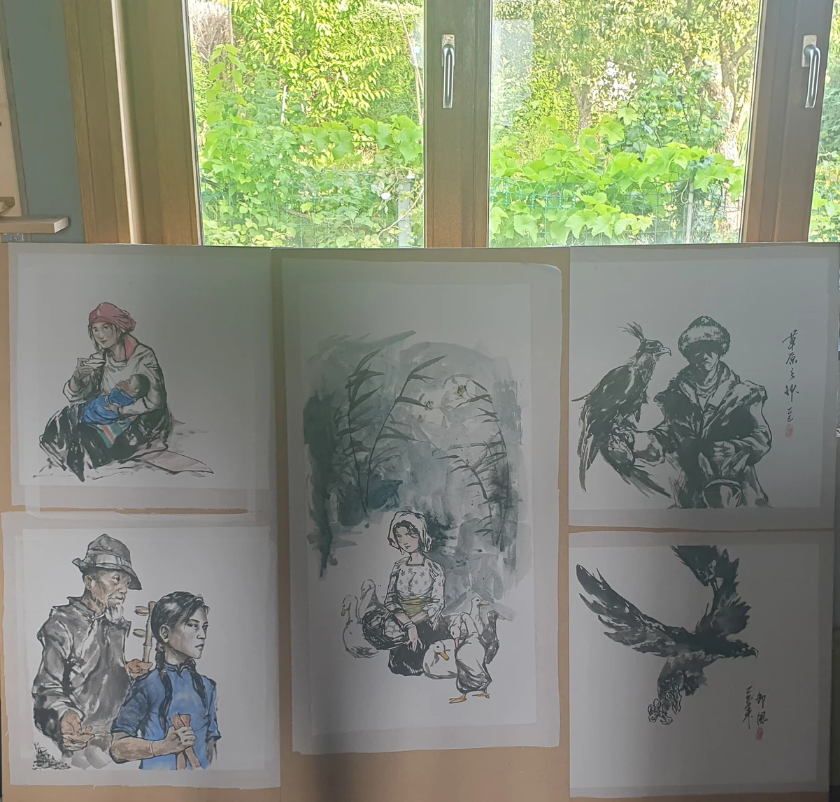 Mounted paintings drying by the window.